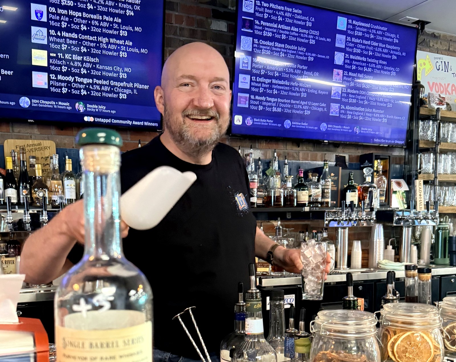 Steve behind the bar at The Brothers Beer & Bourbon House in Ballwin, MO, scooping ice in front of the tap-list display.